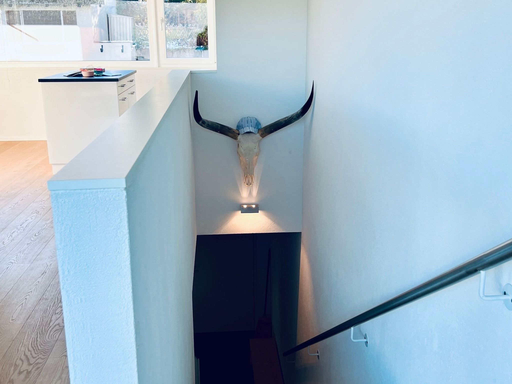 A modern interior with a bull's head mounted on the wall, a staircase, and a view of the outdoors.