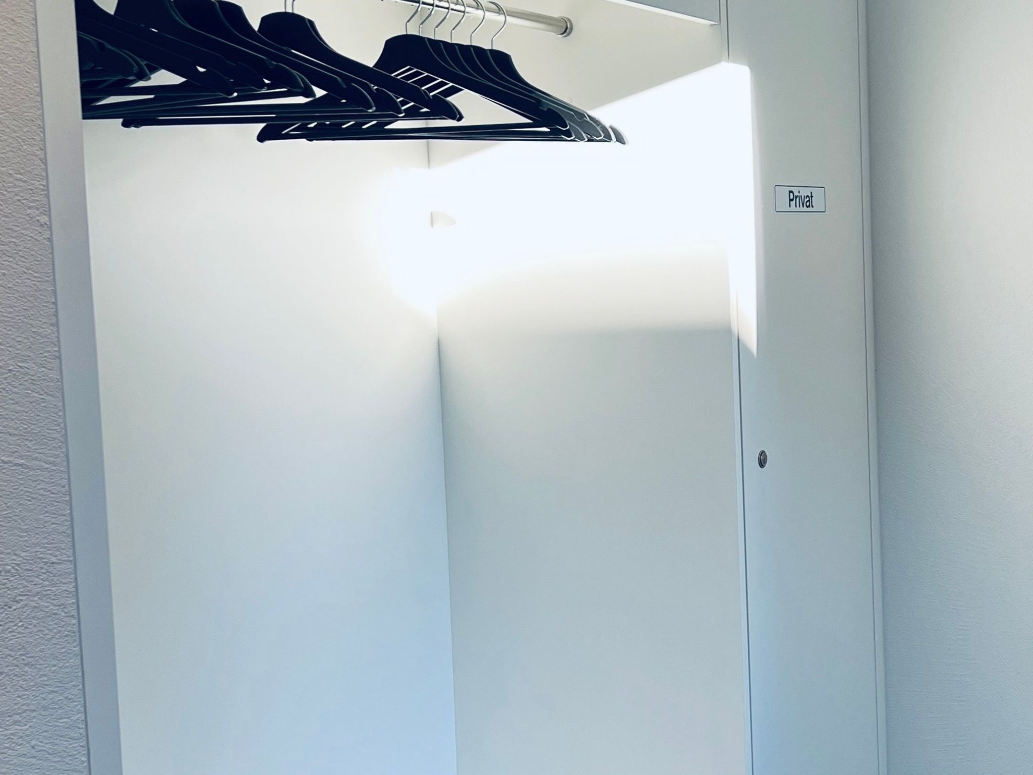 A private room with a door, a coat rack with hangers, and a light switch.