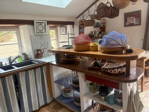 A kitchen with a wooden island, shelves with dishes, and hanging baskets. - Spacious house in a quiet area - 12 guests (Auvers-le-Hamon)