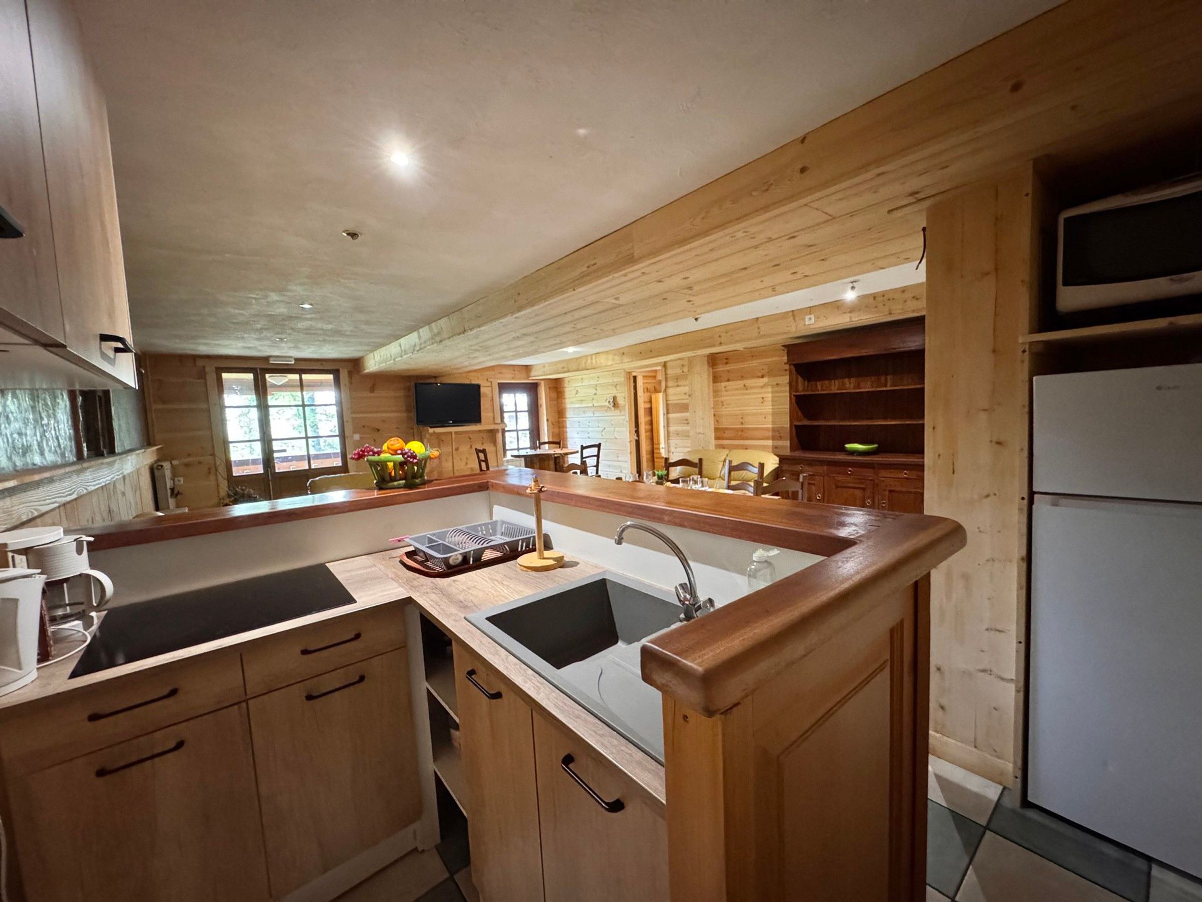 A kitchen with wooden cabinets, a central island with a sink, and a built-in oven.