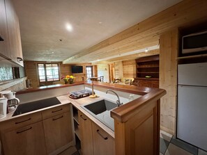 Eine Küche mit Holzausstattung, einer zentralen Kochinsel mit Spüle und einem Einbauofen.