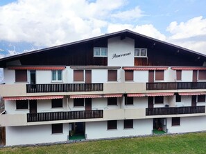 Un edificio a più piani con balconi, un cartello che recita 'Panorama' e montagne sullo sfondo.