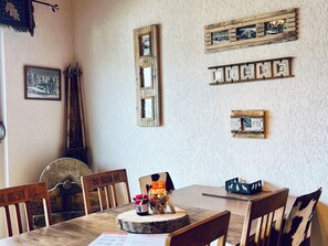Zona pranzo con sedie in legno e un tavolo, quadri appesi alle pareti e un arredamento rustico.