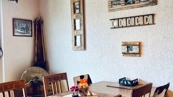 Ein Essbereich mit Holzböcken, einem Holztisch und Bilderrahmen an der Wand.