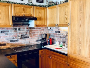 A kitchen with wooden cabinets, a brick backsplash, a stove, and various kitchen appliances.