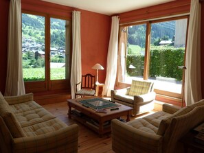Una habitación acogedora con ventanas amplias, suelo de madera y mobiliario escocés.