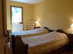 Un dormitorio con dos camas, una silla y dos lámparas de noche.