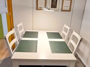 Een rechthoekige tafel met vier stoelen, elk met een groene zitting.