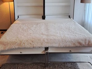 Ein Bett mit einer flauschigen, weißen Matratze und einem Metallgestell.