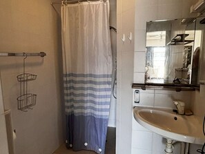 A bathroom with a shower curtain, a sink, a mirror, and a towel rack. - Apartment ADA with view - 4 guests (Le Barcarès)