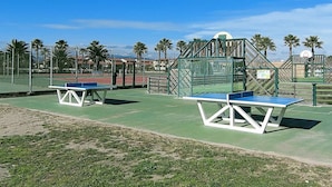 Ein Außen-Tennisplatz mit zwei Tischen und einem Basketballkorb.