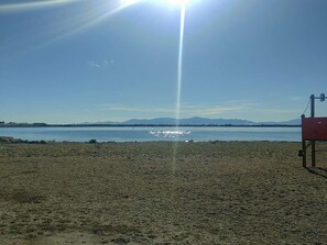 A beach with a clear sky, a body of water, and distant mountains. - Apartment ADA with view - 4 guests (Le Barcarès)