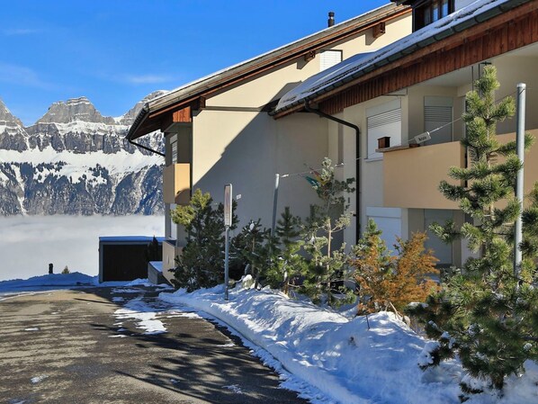 A hotel with a mountain view, snow-covered ground, and a clear sky.