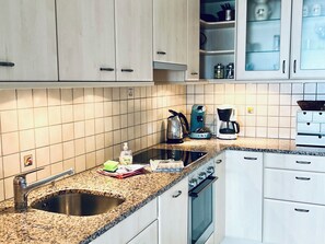 A kitchen with a granite countertop, stainless steel sink, and a coffee maker.