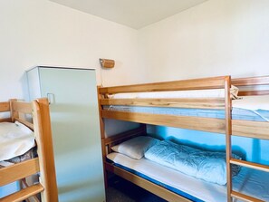 Ein Schlafraum mit Etagenbett, einem Einzelbett und einem kleinen Schrank.
