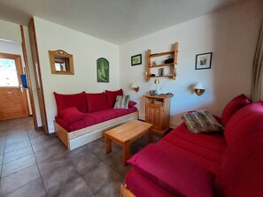 Ein Wohnzimmer mit einem roten Sofa, einem Holztisch und einer Holzkommode mit einer Lampe.