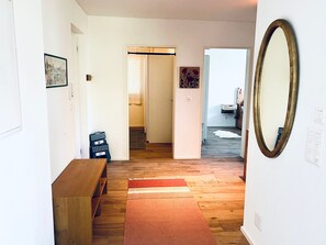 Ein Flur mit einer hölzernen Bank, einem Teppich und einem Spiegel an der Wand.