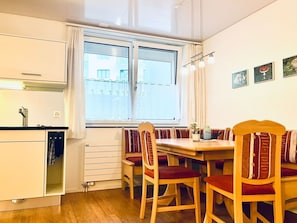 Eine kleine Küche mit Fenster, einem Holzespeisetisch und Stühlen.