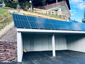 A building with a sloped roof covered in solar panels, a stone staircase, and a wooden fence. - Chalet Windegg (CharmingStay), (Flumserberg Tannenheim), by Interhome (Flumserberg Tannenheim)