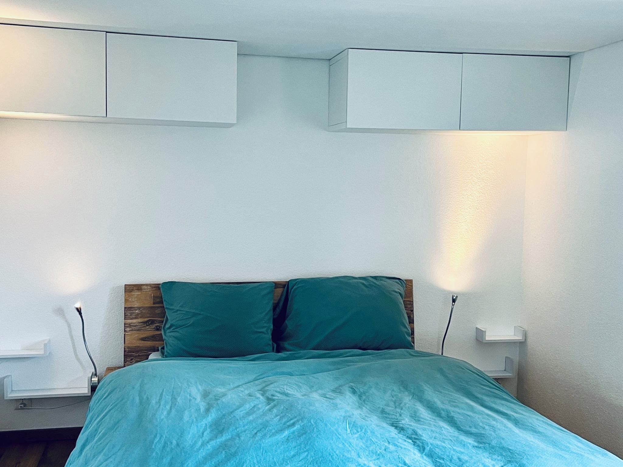 Ein Schlafzimmer mit einem Bett, zwei Nachttischen und zwei an der Wand befestigten Schränken.
