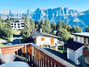 A residential area with a mountain backdrop, featuring a house with a balcony and a view of the mountains.