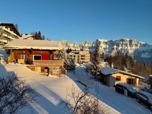 A snow-covered mountain resort with wooden cabins and a ski lift.