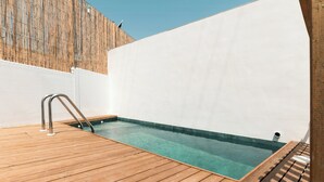A wooden deck leading to a clear pool with a metal ladder, surrounded by white walls. - House with a pool, ideal for visiting Andalusia. (Luque)