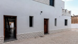 A modern two-story building with a flat facade, multiple windows, and a gravel courtyard. - House with a pool, ideal for visiting Andalusia. (Luque)