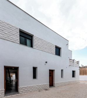 Un edificio moderno de dos pisos con fachada plana, varias ventanas y un patio de grava.