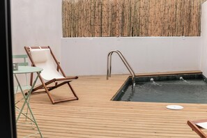 A wooden deck with a pool, a lounge chair, and a small table. - House with a pool, ideal for visiting Andalusia. (Luque)