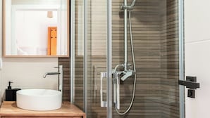 A modern bathroom with a glass-enclosed shower, a wooden vanity, and a white sink. - House with a pool, ideal for visiting Andalusia. (Luque)