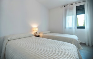 Een kamer met twee bedden, een bedlampje en een raam met gordijnen.