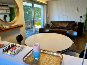 A modern living room with a large oval table, a chessboard, and a tray with a drink. - Chalet Tännli (CharmingStay), (Flumserberg Tannenbodenalp), by Interhome (Flumserberg Tannenbodenalp)