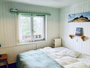 A bedroom with a bed, a window, a shelf with a book, and a painting on the wall. - Chalet Tännli (CharmingStay), (Flumserberg Tannenbodenalp), by Interhome (Flumserberg Tannenbodenalp)
