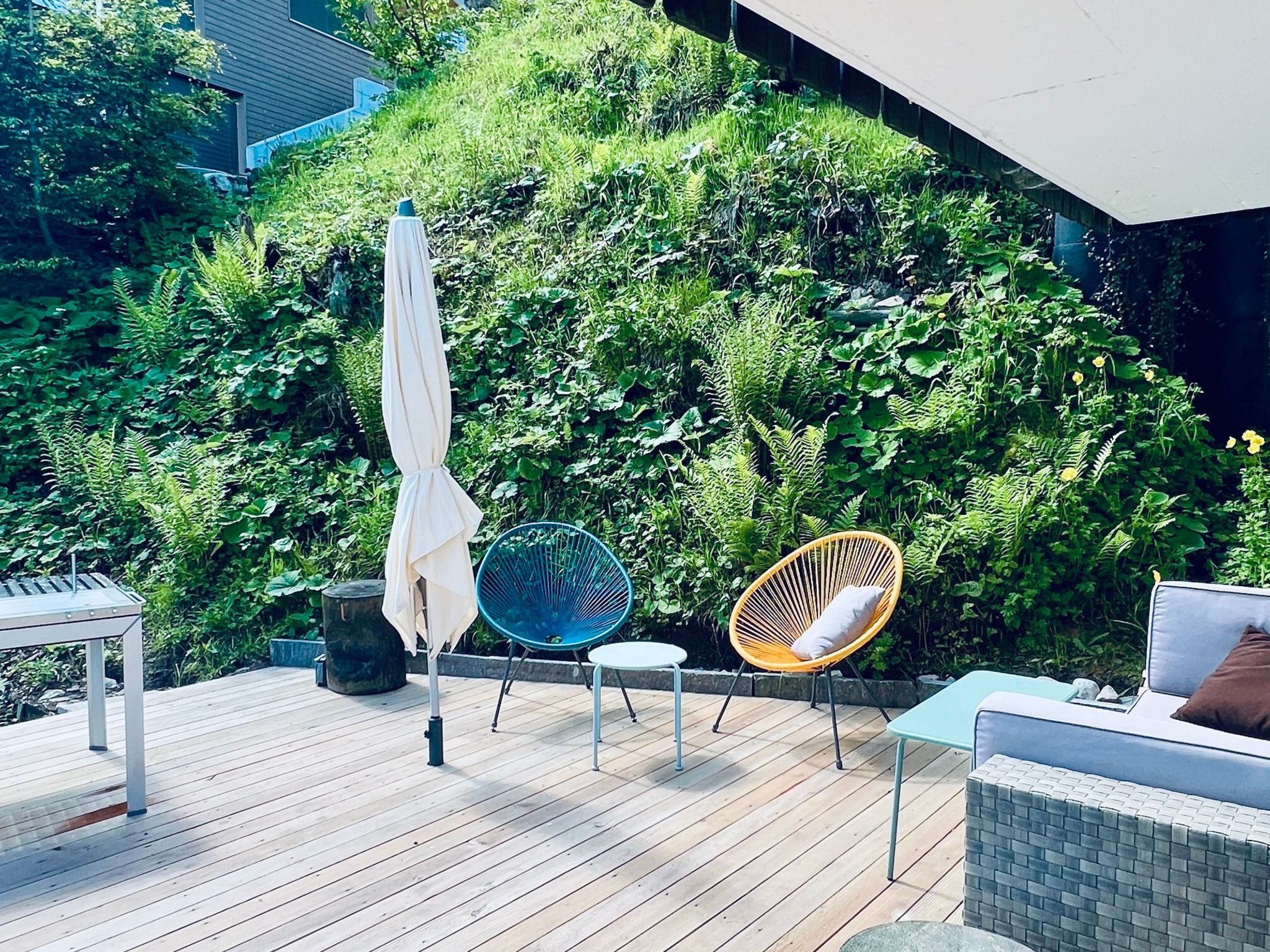 A wooden deck with outdoor furniture, including a table, chairs, and a sofa.