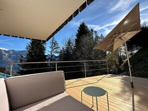 A deck with a sofa and a table, overlooking a mountainous landscape. - Chalet Tännli (CharmingStay), (Flumserberg Tannenbodenalp), by Interhome (Flumserberg Tannenbodenalp)