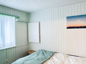 A room with a bed, a small wooden stool, a window with a sheer curtain, and a wall-mounted picture. - Chalet Tännli (CharmingStay), (Flumserberg Tannenbodenalp), by Interhome (Flumserberg Tannenbodenalp)