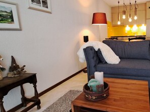 Ein Wohnzimmer mit einer Couch, einer Lampe, einem Tisch mit einer Kerze und einer dekorativen Schale.