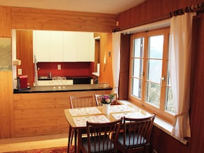 A wooden interior with a kitchen, dining area, and a window with curtains. - Chalet Schwendihus (CharmingStay), (Flumserberg Tannenbodenalp), by Interhome (Mols)