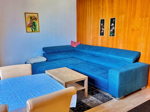 A living room with a blue sectional sofa, a small wooden coffee table, and a patterned rug. - Chalet Schwendihus (CharmingStay), (Flumserberg Tannenbodenalp), by Interhome (Mols)