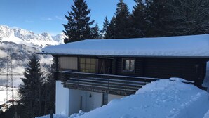 En hytte med balkon, omgivet af sne og bjerge.