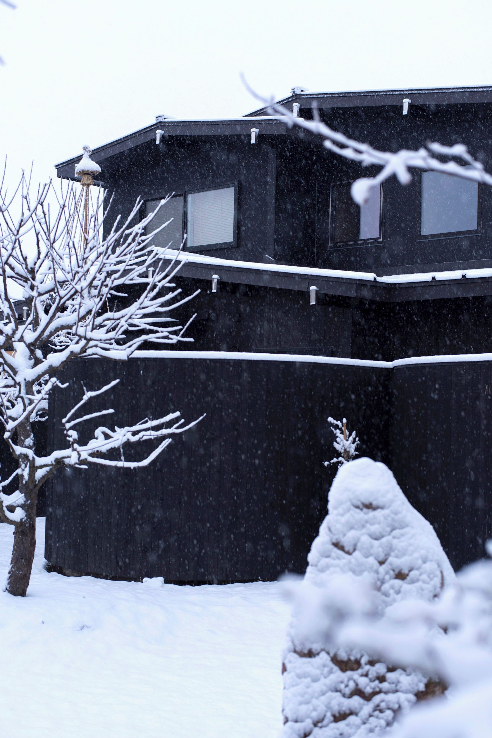 Un bâtiment à l’extérieur sombre, doté de nombreuses fenêtres, et un paysage enneigé.
