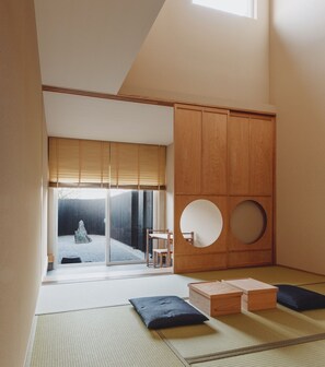 Camera dal design minimalista, con pavimento in tatami, scorrevole che dà su uno spazio esterno e un armadio tradizionale giapponese.