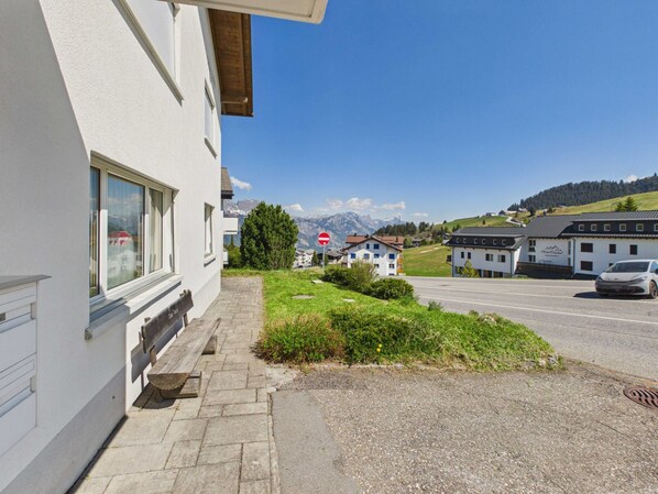 A hotel with a paved driveway, a bench, and a view of mountains in the background.