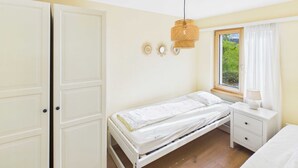 Una camera da letto con un letto singolo, un comodino, una finestra con tende e un punto luce a parete.