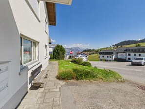 En byggnad med en belagd entré, en bänk och utsikt över en väg med en bil.