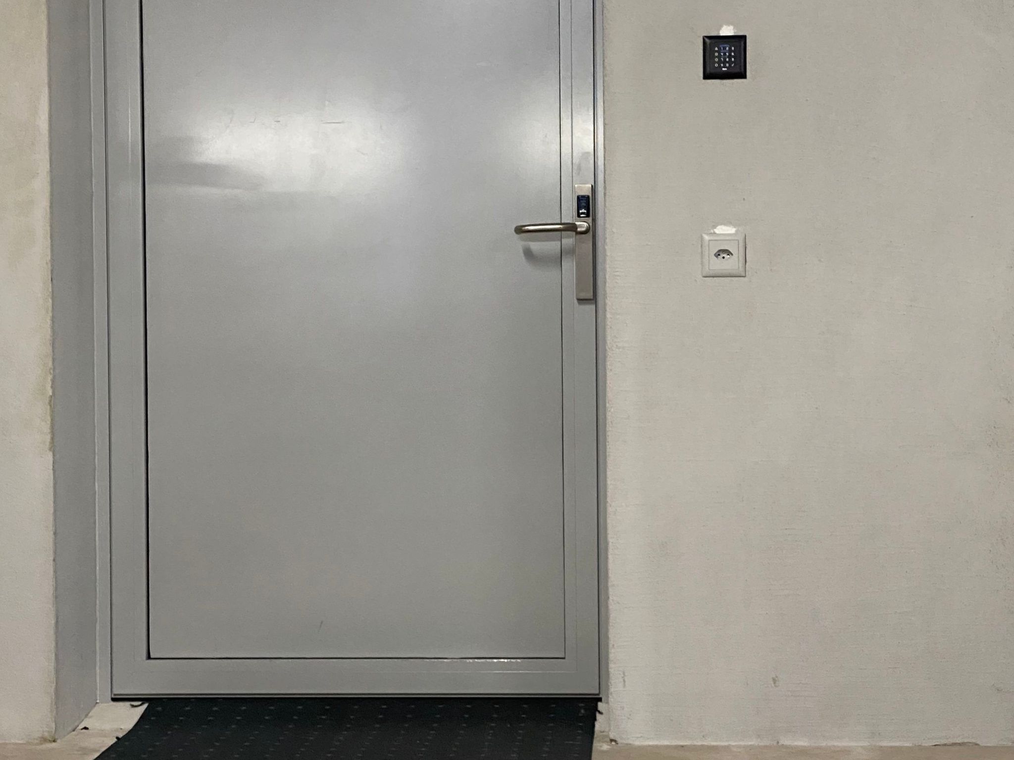 A closed door with a metal handle and a small electronic keypad lock.