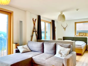 Ein modernes Schlafzimmer mit einer Couch, einem Bett, einem Schreibtisch und einem Skiständer.