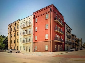 A multi-story building with a red facade and multiple balconies. - Tiger Condo at LSU!  Walk to Tiger Stadium & PMAC! (Baton Rouge)