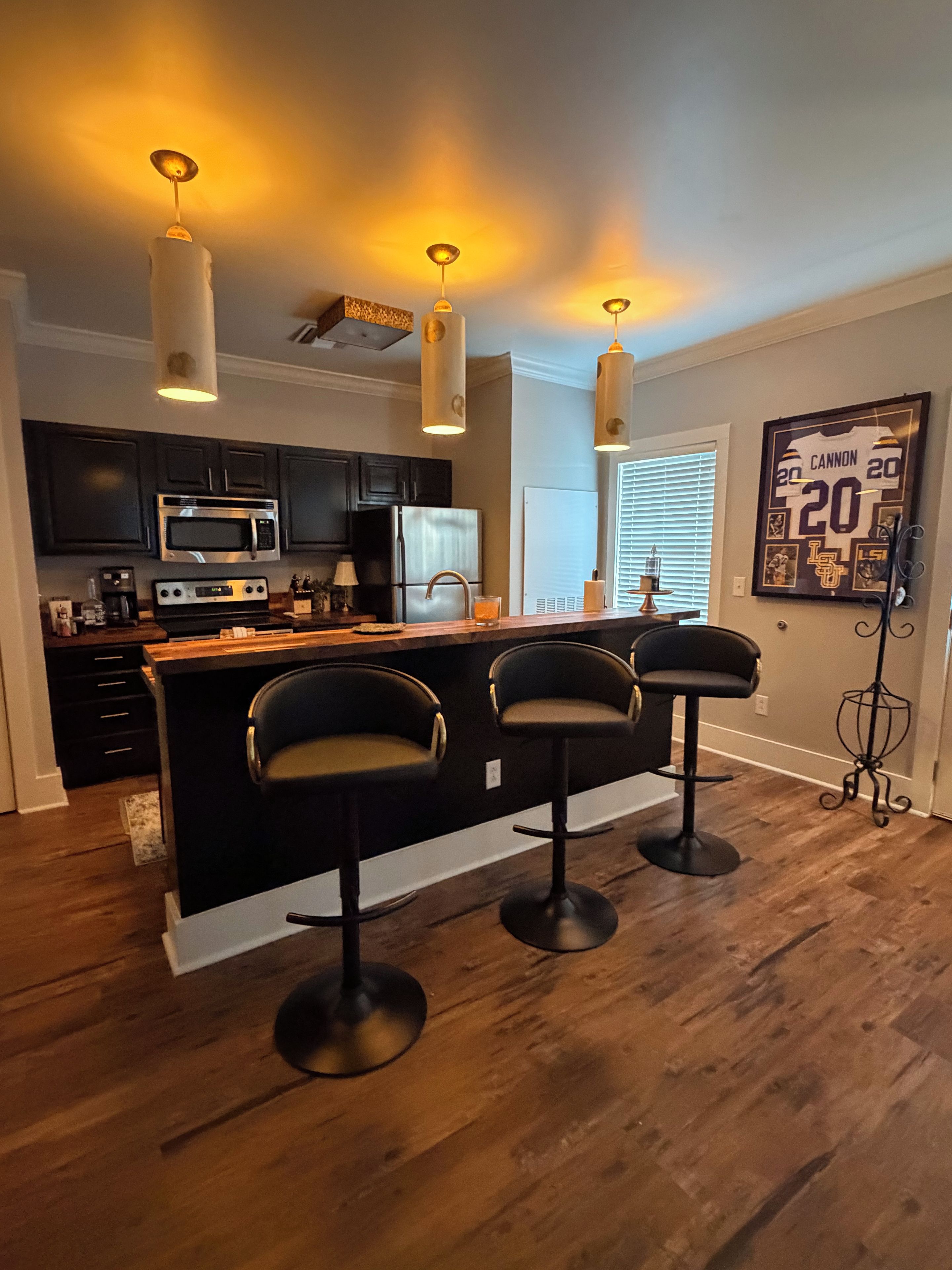 A modern kitchen with dark cabinetry, a central island with bar stools, and pendant lighting.